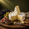Brie-style cheese with grapes, figs and oatcakes on a wooden board